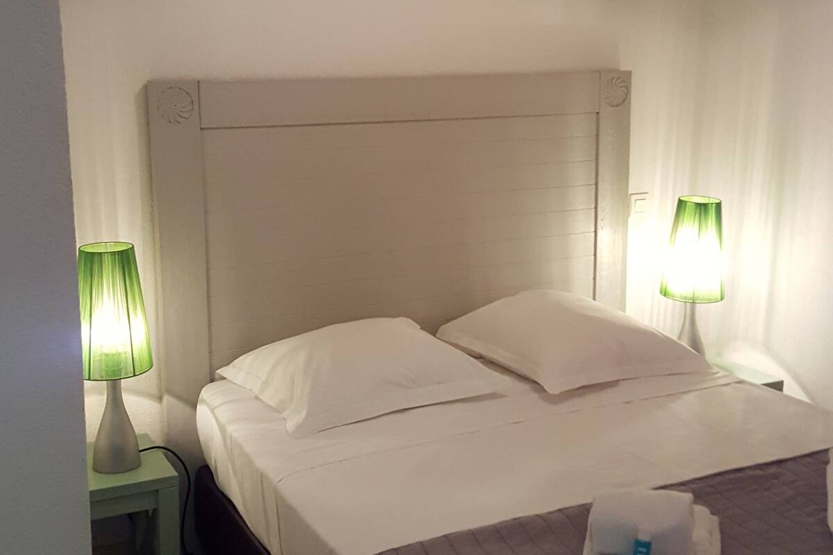 A hotel room with a single bed, two bedside lamps, a nightstand, and a ceiling light.