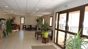 A spacious lobby with a reception desk, seating area, and potted plants.
