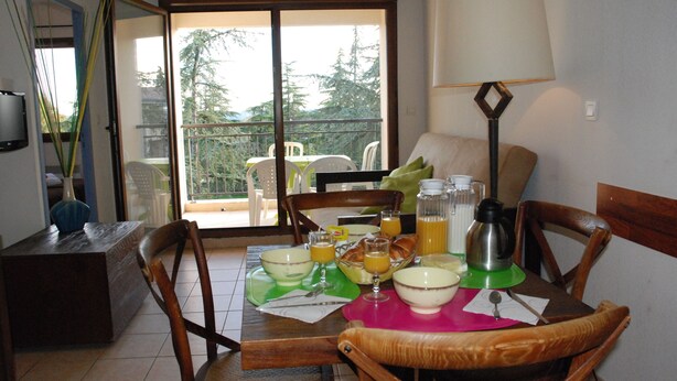 A dining area with a table set for breakfast, including bowls, glasses, and a coffee pot.