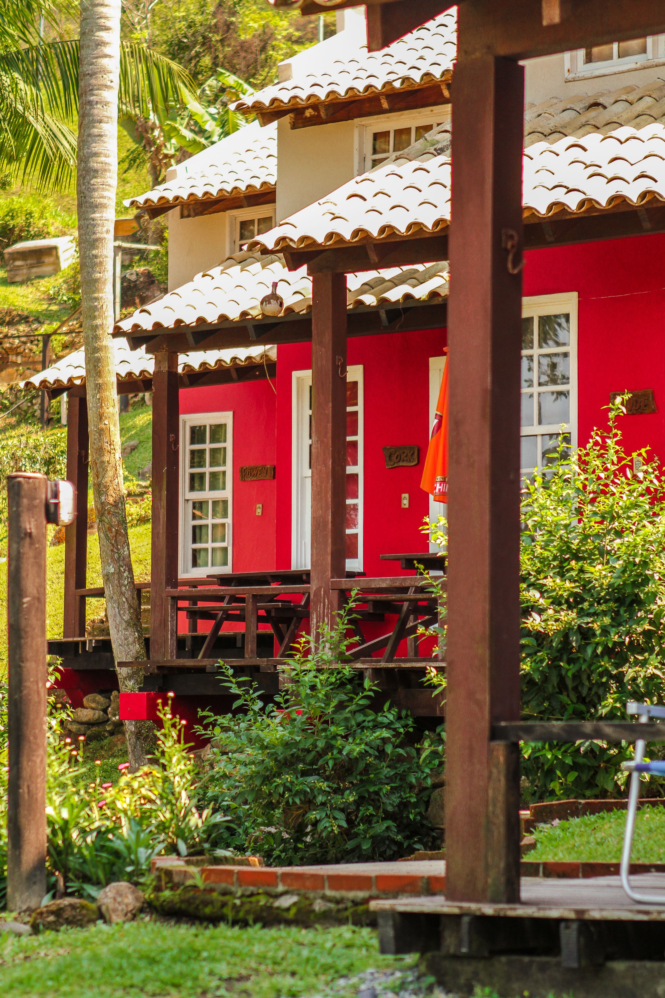 Um edifício vermelho com telhado de telhas, vigas de madeira e um pequeno alpendre.