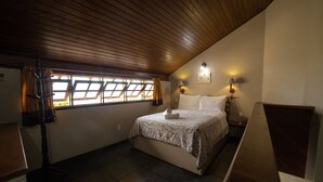 A bedroom with a bed, a desk, a lamp, and a window with curtains. - Pousada dos Ingleses (Bombinhas)