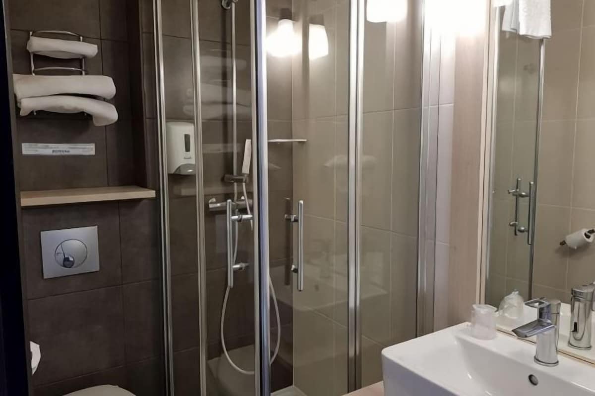 Ein modernes Badezimmer mit einer Glaskabine zur Dusche, einer Toilette und einem Waschbecken mit Spiegel.