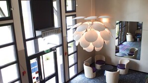 A modern interior with large windows, a unique spherical chandelier, and a seating area with round tables and chairs. - Hôtel Inn Design & Restaurant Rochefort (Rochefort)