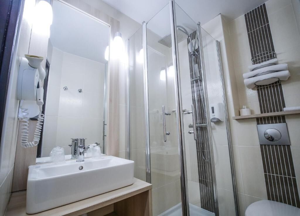 A modern bathroom with a glass-enclosed shower, a white sink, and a toilet.