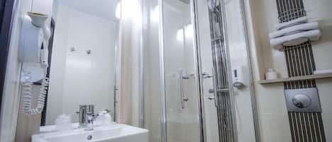 A modern bathroom with a glass-enclosed shower, a white sink, and a toilet.