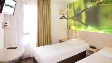Ein Hotelzimmer mit Bett, Nachttisch, Lampe und einem Fernseher, der 'HOTEL INN' anzeigt.