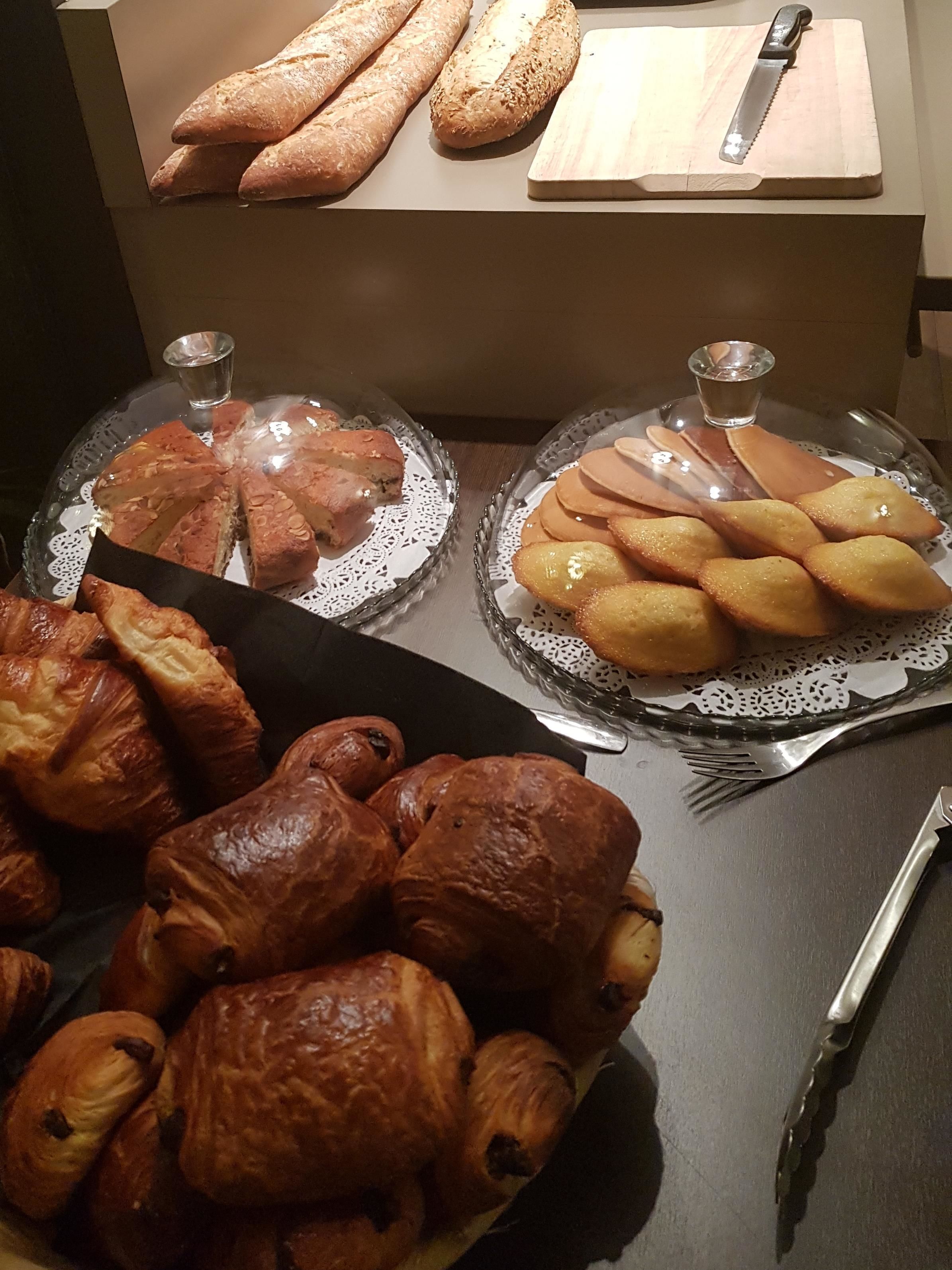 A table with various baked goods, including bread and pastries, and a knife on a cutting board.