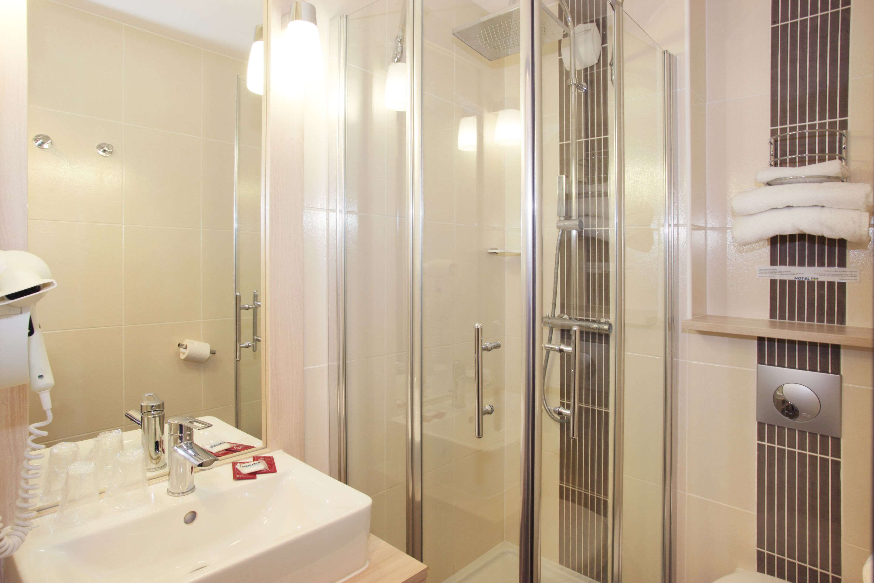 A modern bathroom with a glass-enclosed shower, a sink with a mirror, and a towel rack.