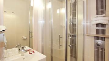 A modern bathroom with a glass-enclosed shower, a sink with a mirror, and a towel rack.