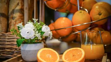 A tray with oranges, a glass of orange juice, and a floral arrangement.