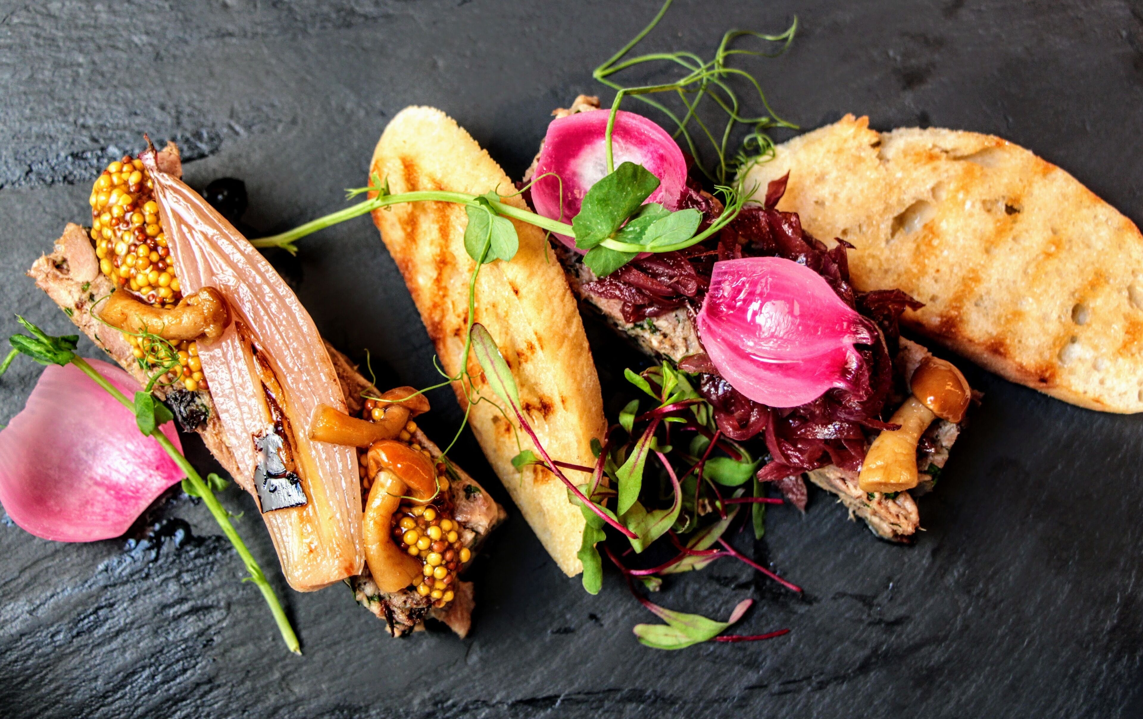 Un assortiment de plats comprenant un sandwich à la croûte croustillante, une tranche de pain et une salade de radis et de jeunes pousses.