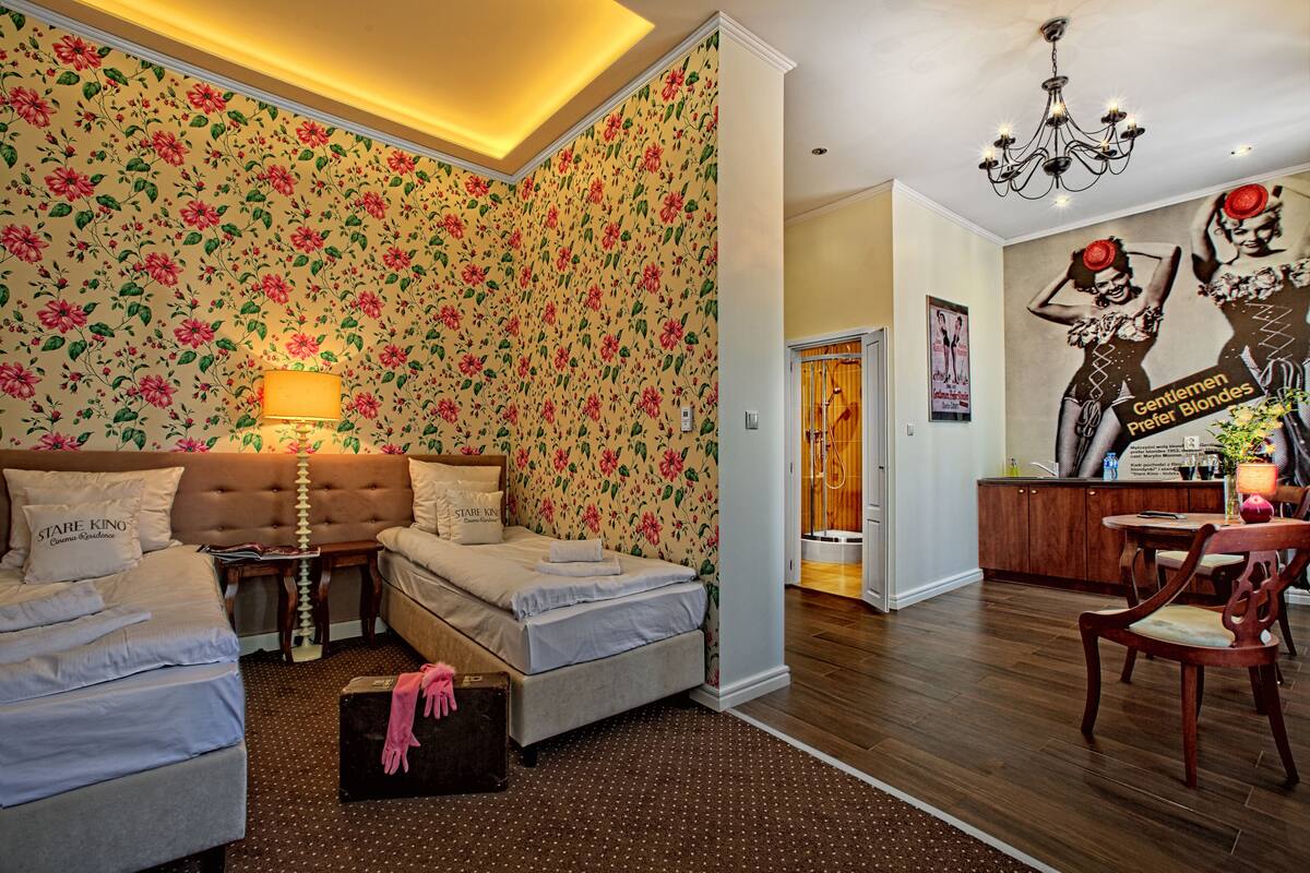 Ein Schlafzimmer mit blumigem Wandpapier, einer Kristallleuchtre und einem Poster an der Wand.