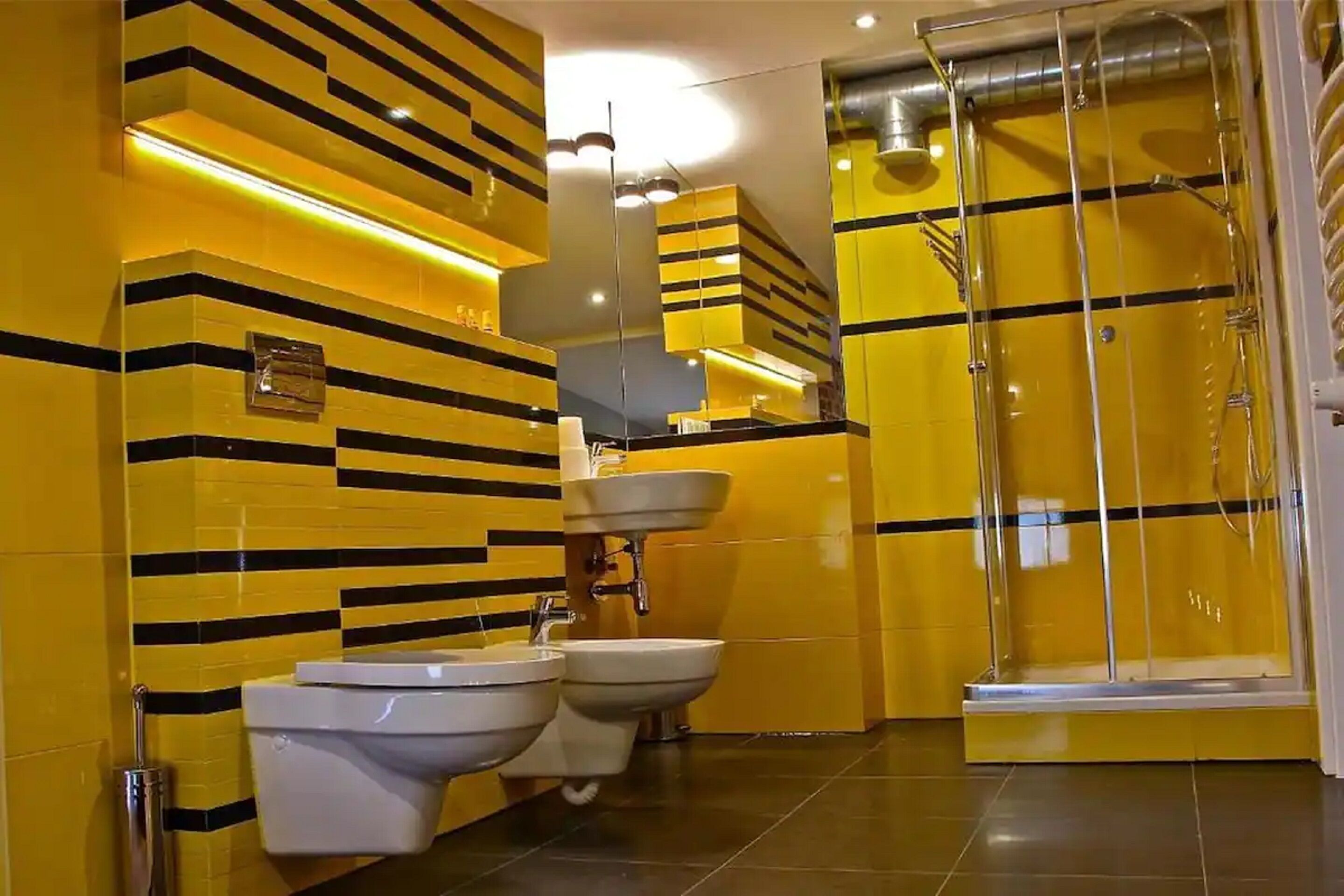 A bathroom with yellow and black striped walls, a glass shower enclosure, and two sinks.
