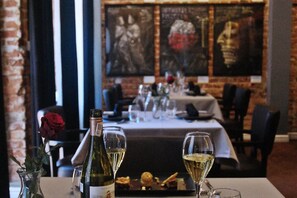 L’intérieur d’un restaurant, avec une table dressée pour le dîner, agrémentée d’une bouteille de vin, de verres et d’une rose.