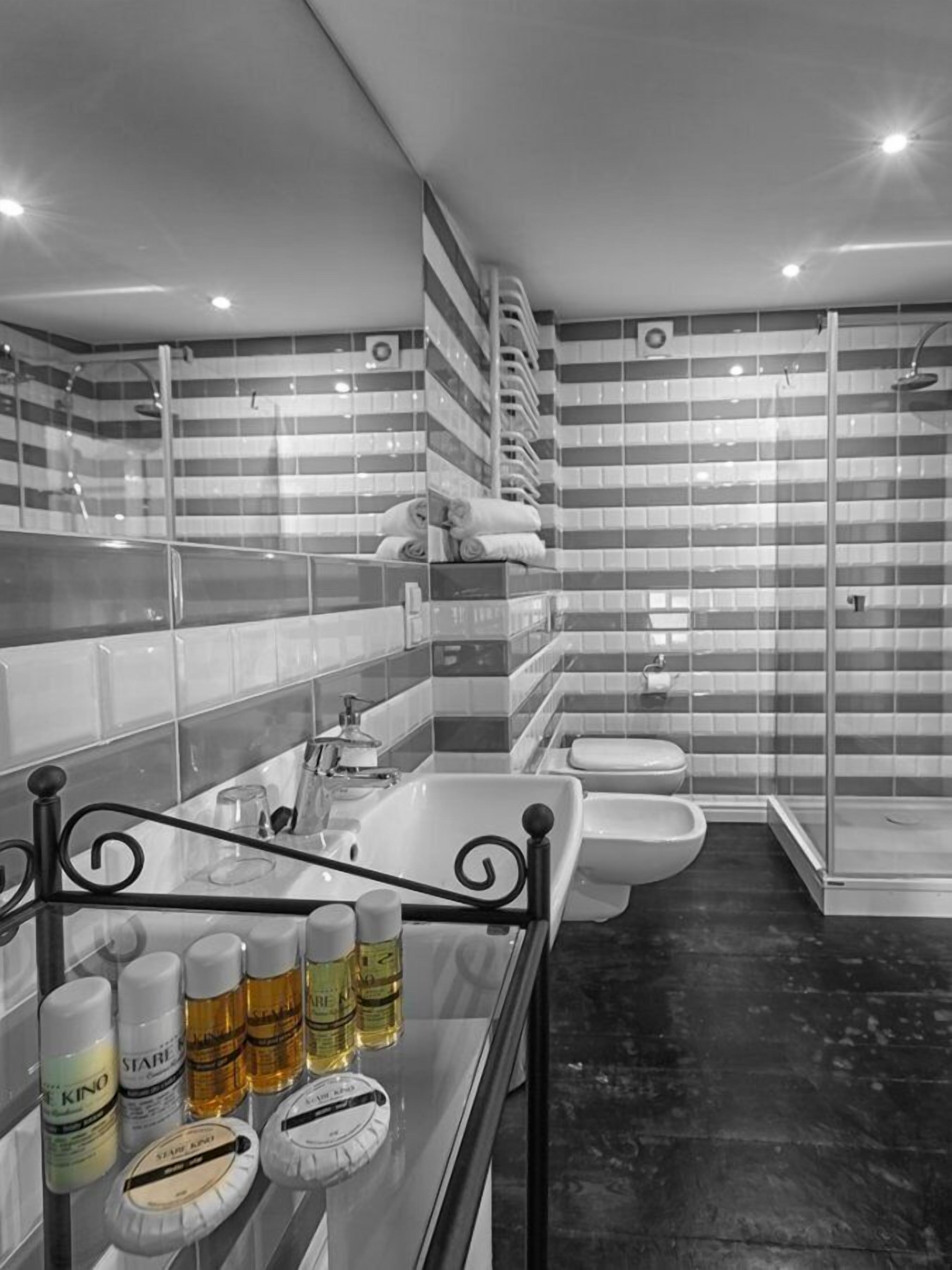 A modern bathroom with a glass shower enclosure, a large mirror, and a vanity with toiletries.