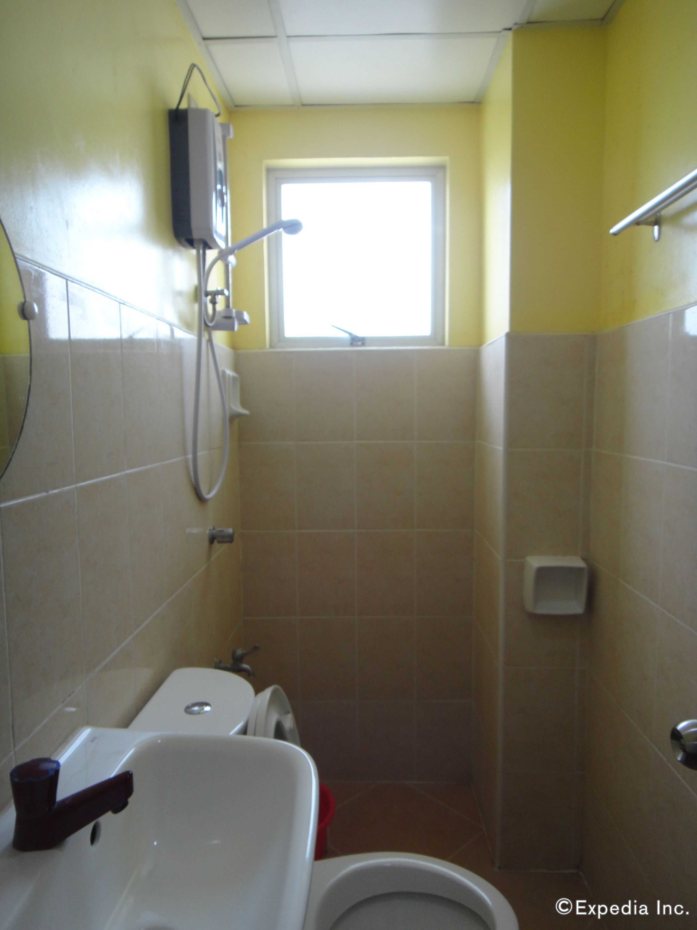 A bathroom with a toilet, sink, and shower. There is a window above the shower.