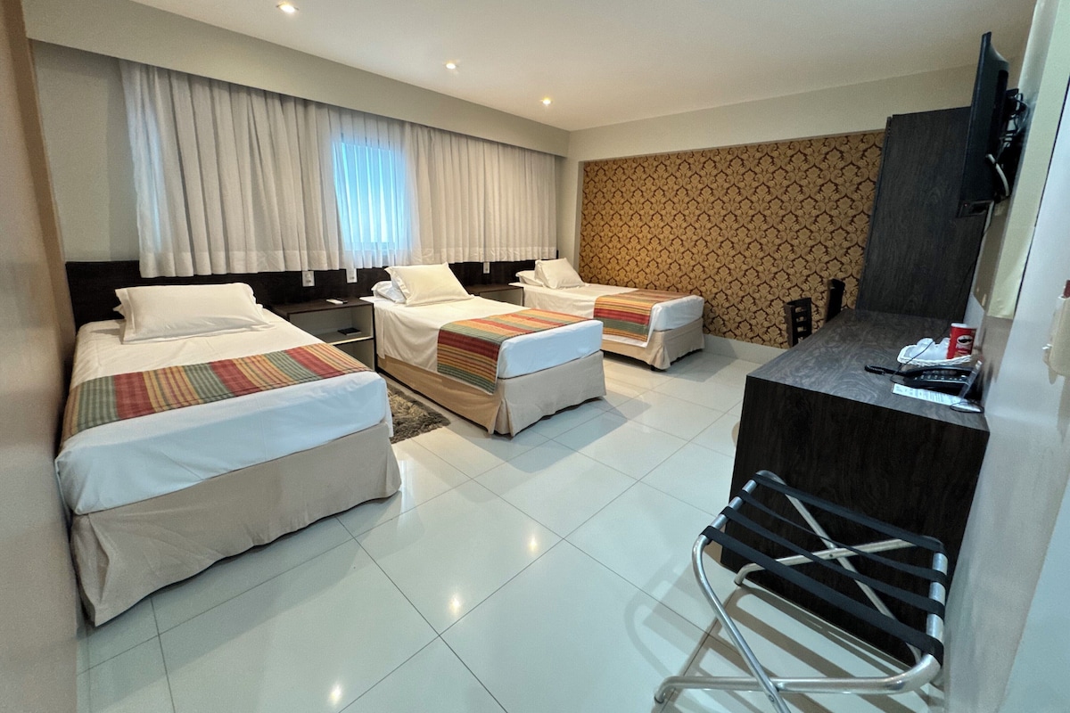 Una habitación de hotel con dos camas, un escritorio, una silla y un televisor.