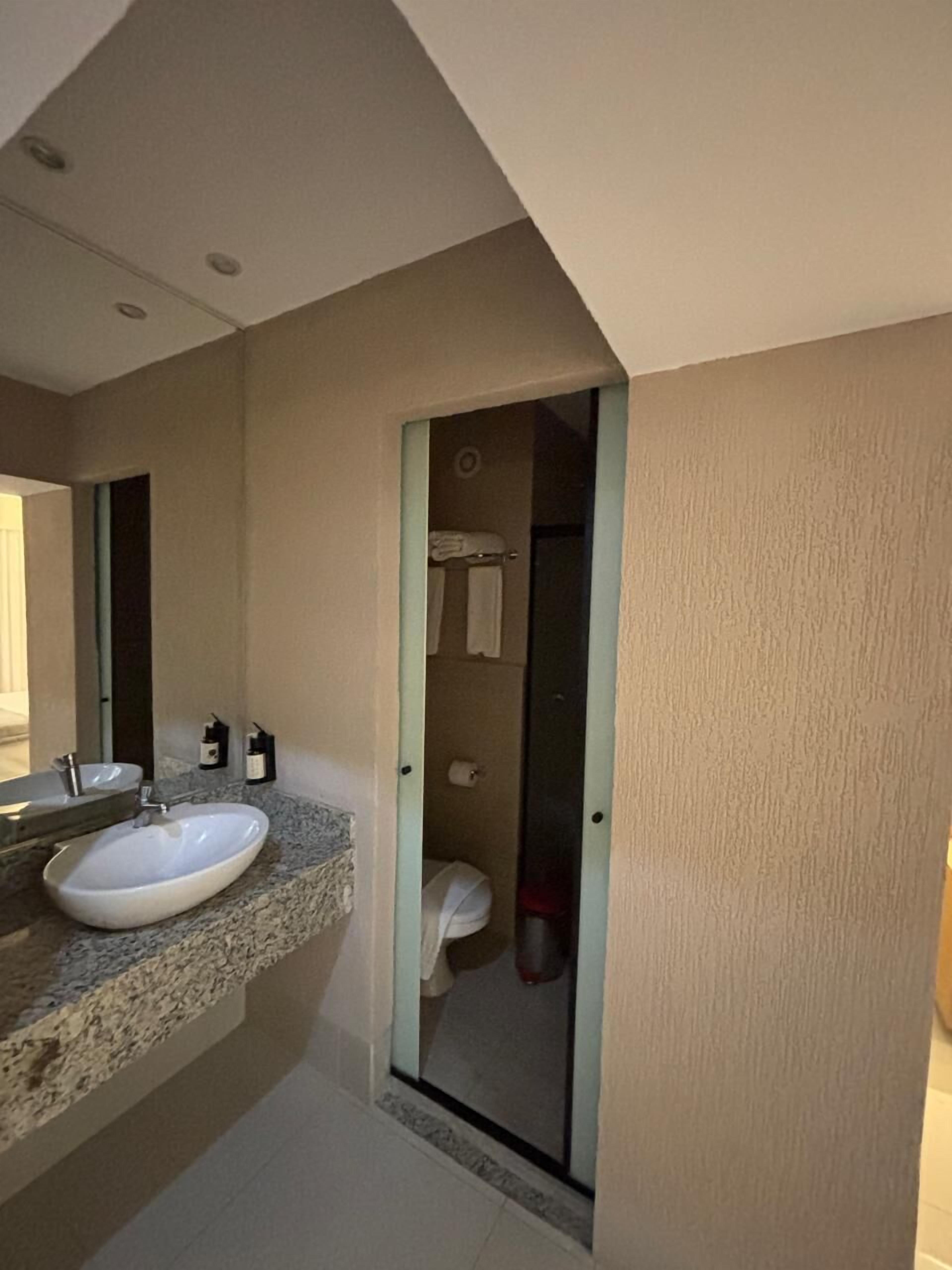 Een badkamer met een witte wastafel, een spiegel en een douchecel achter een glazen deur.