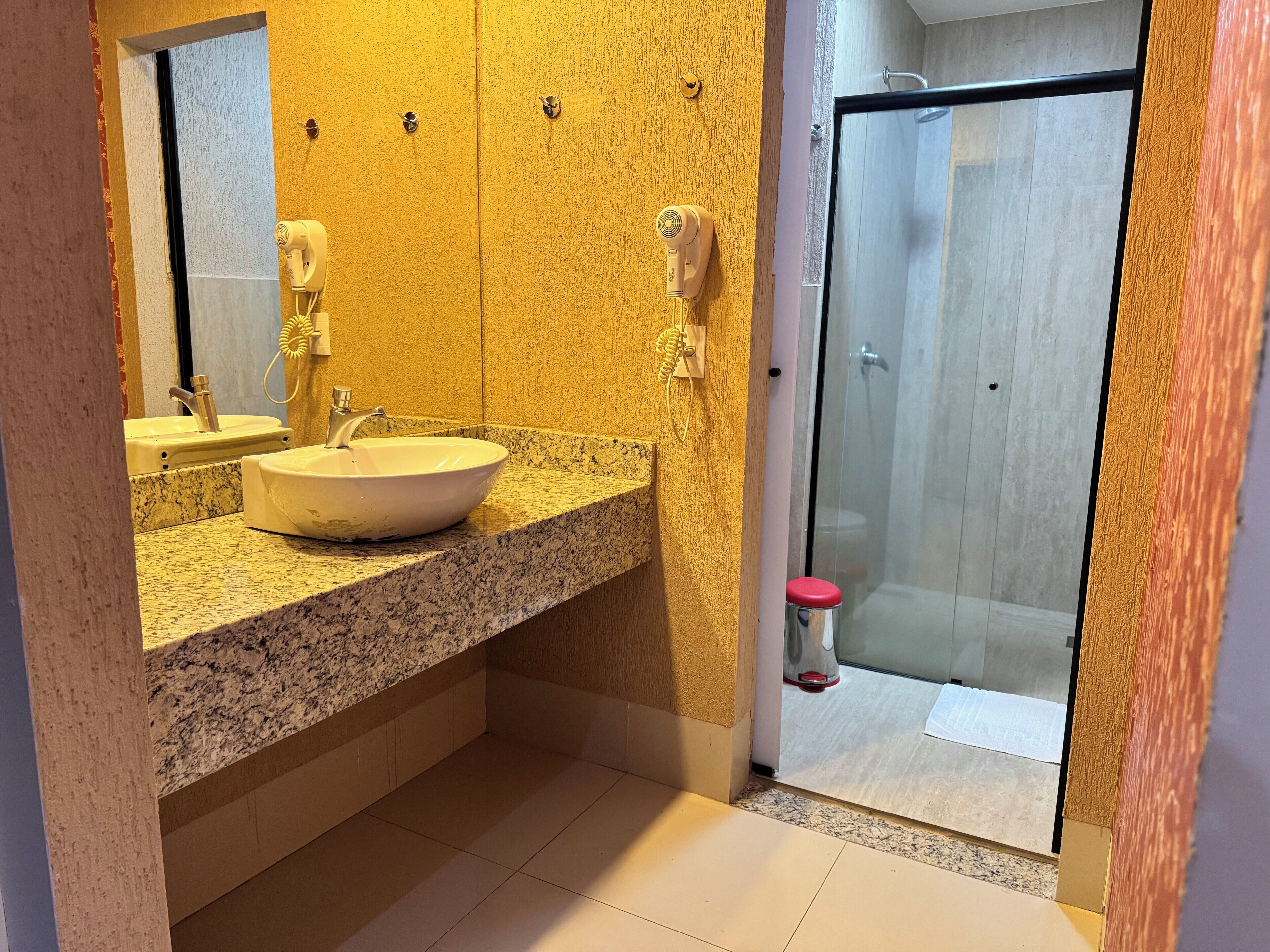 A bathroom with a granite countertop, a white sink, and a glass shower enclosure.
