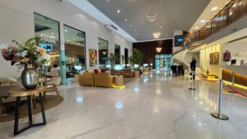 A spacious lobby with a polished marble floor, comfortable seating areas, and a piano.