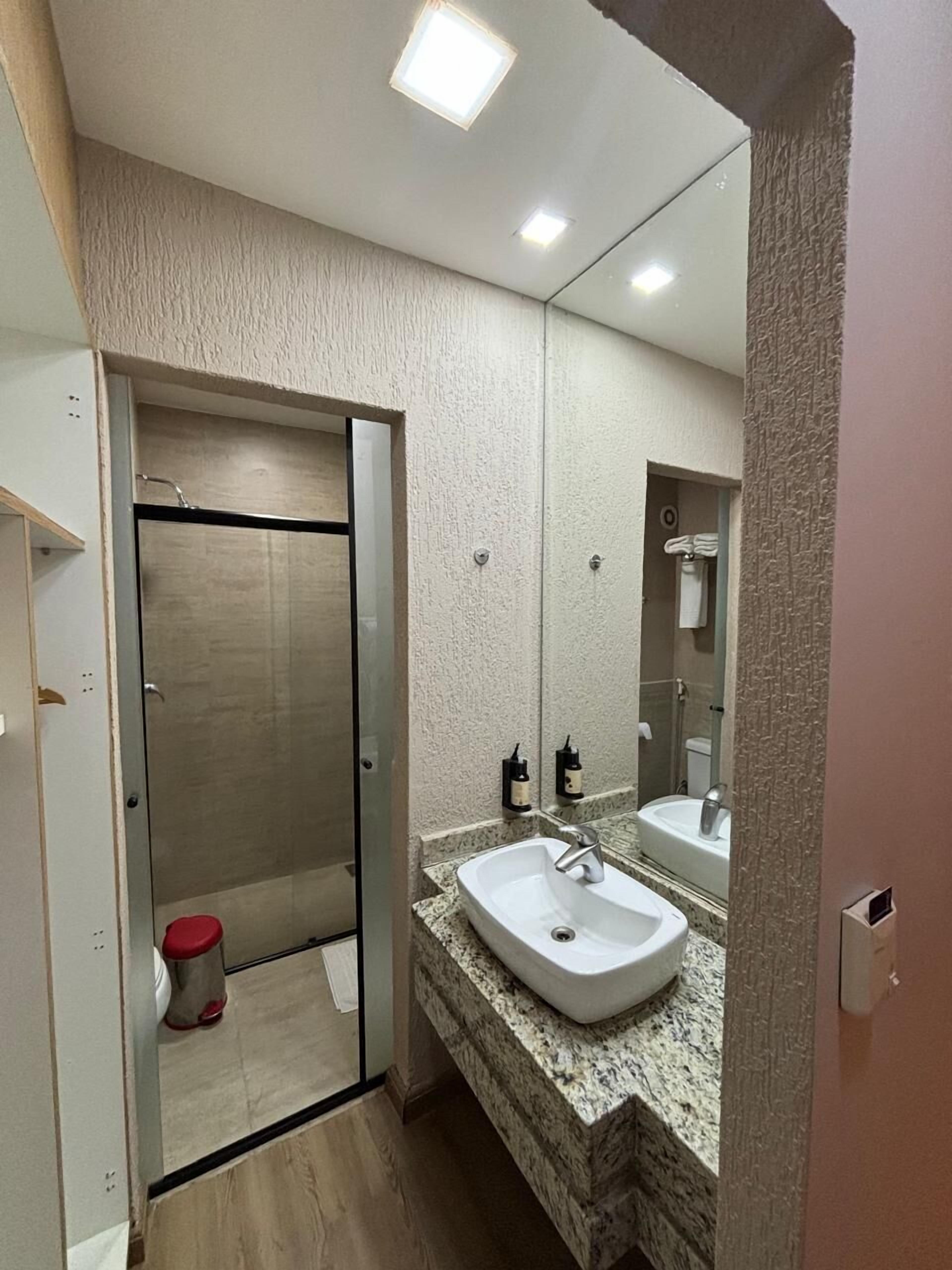 Un bagno moderno con doccia a porta di vetro, un lavandino bianco e uno specchio grande.