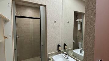 Un bagno moderno con doccia a porta di vetro, un lavandino bianco e uno specchio grande.