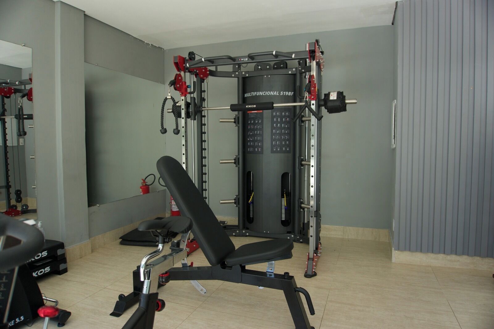 Een sportschool met een squatrek, bank en diverse gewichthefapparaten.