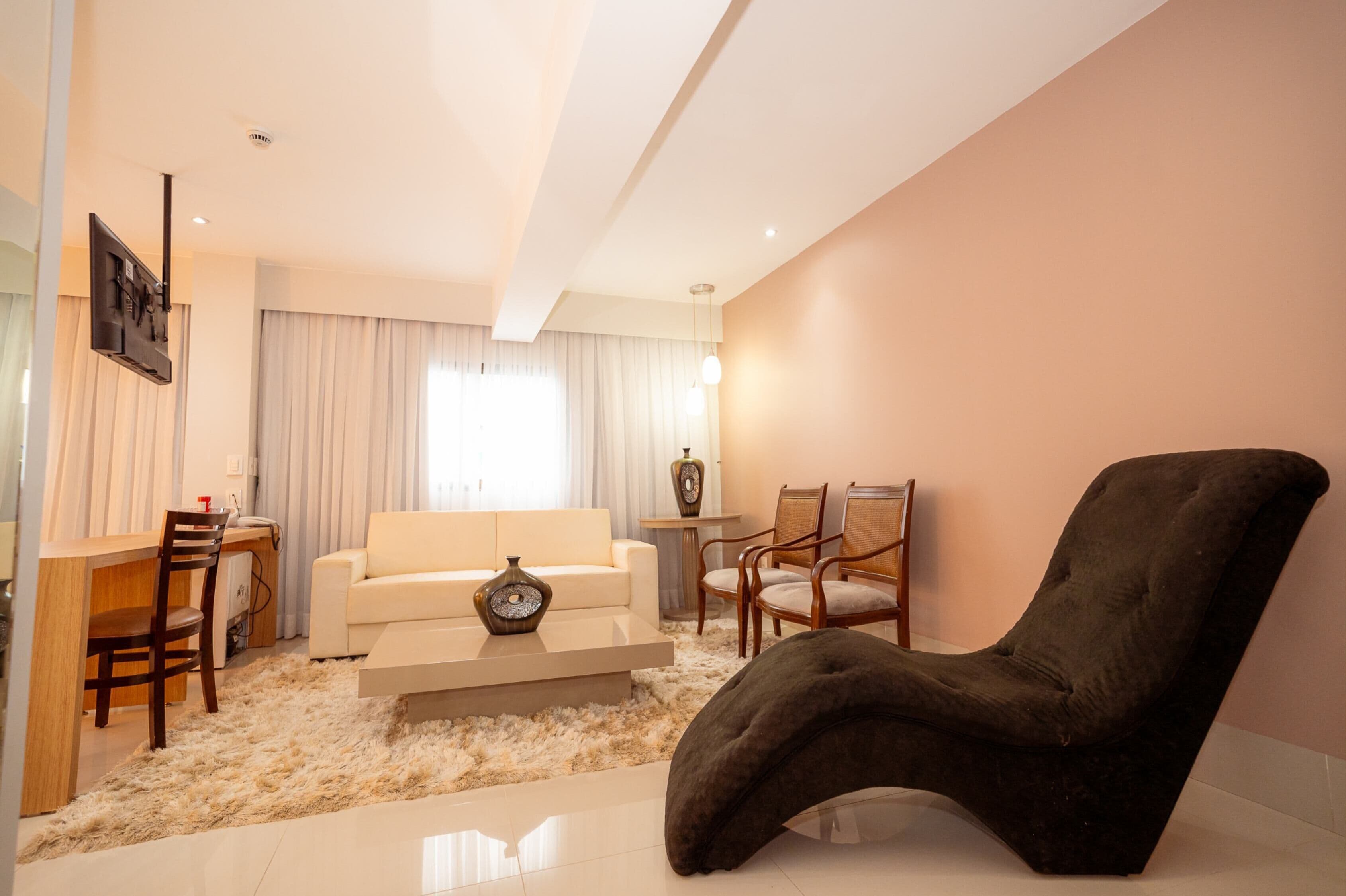 A modern living room with a sofa, chairs, a coffee table, and a flat-screen TV mounted on the wall.