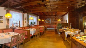 En restaurant med træpaneler, flere spiseborde og et buffetbord med forskellige retter.
