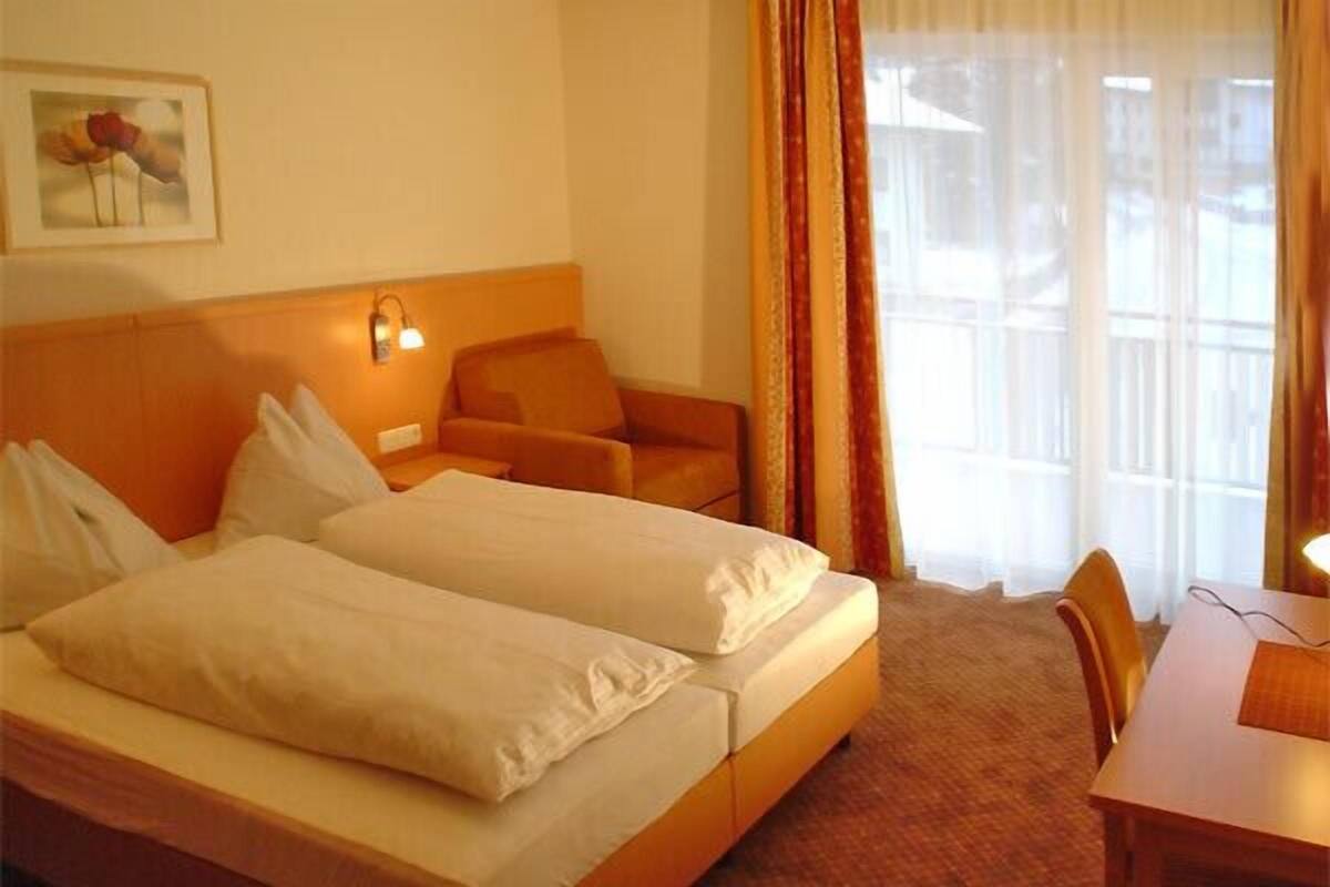 A hotel room with two beds, a desk, and a chair.