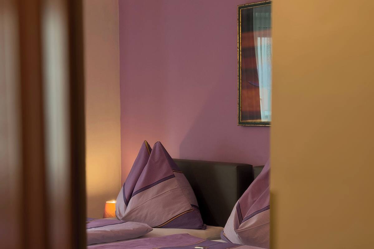 A bedroom with two beds, a nightstand, and a wall-mounted painting.