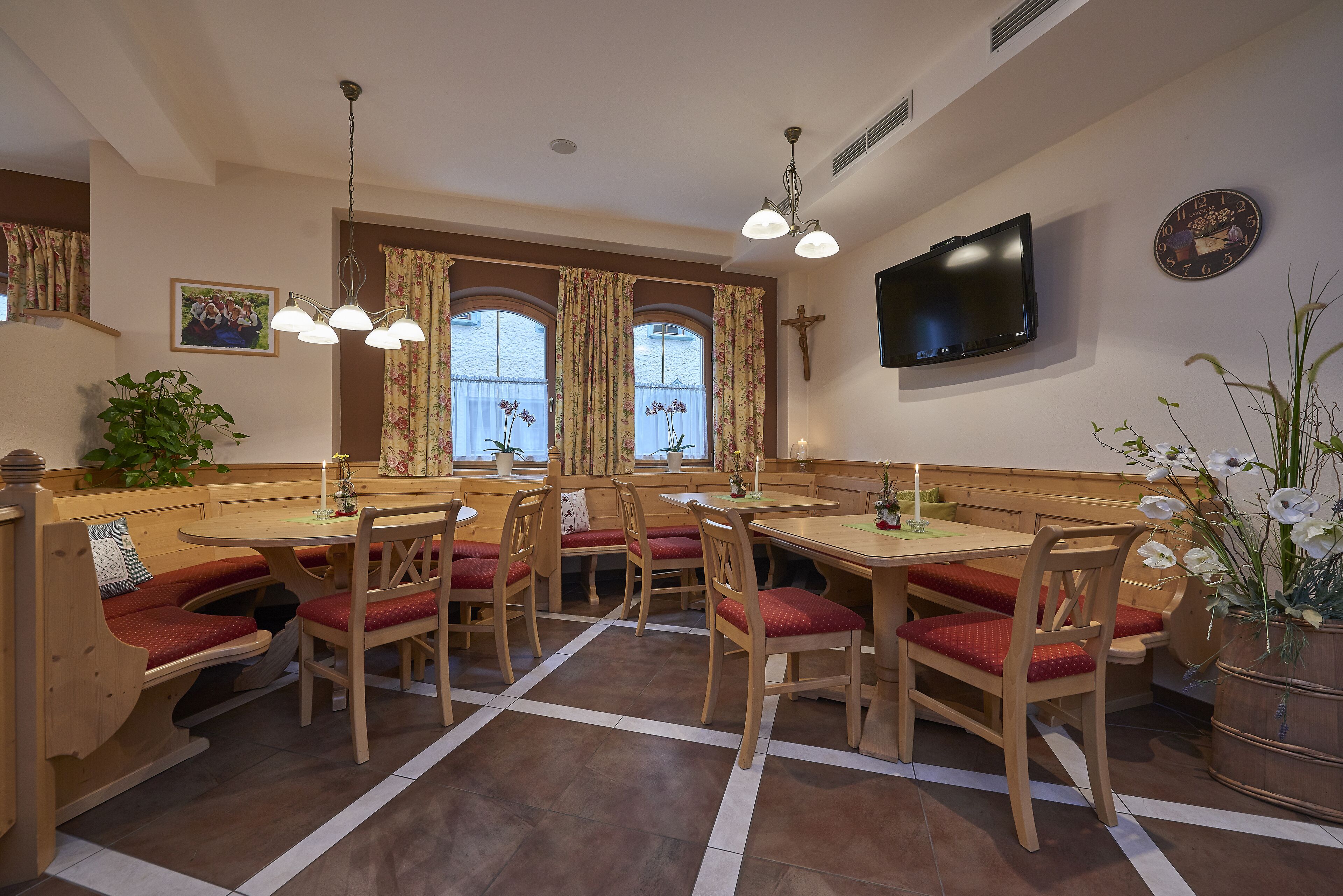 Comedor con muebles de madera, televisor y una cruz en la pared.