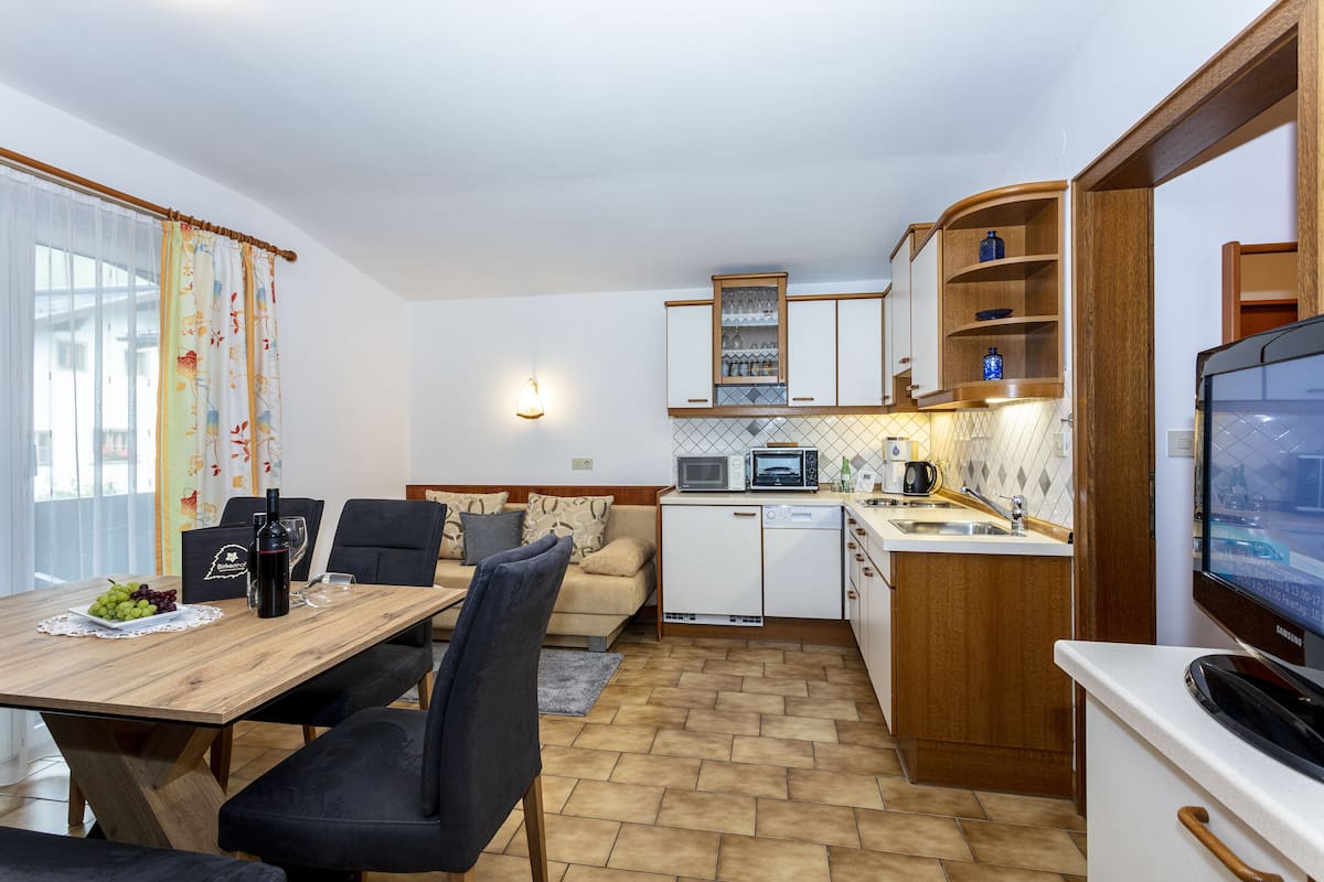 Een kleine keuken met een eethoek, een magnetron, een spoelbak en een televisie.