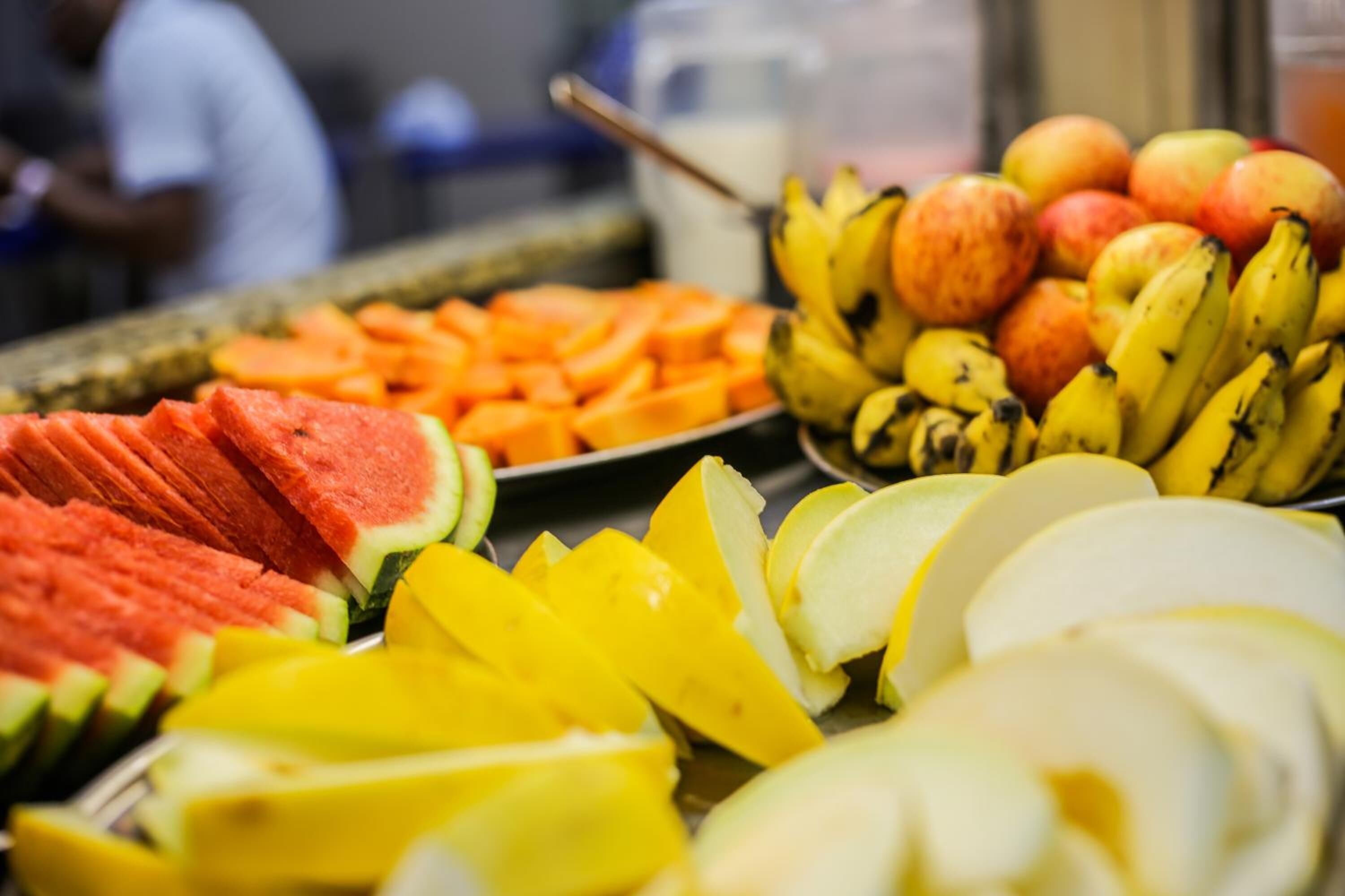 A fruit display with watermelon, mango, bananas, and apples.