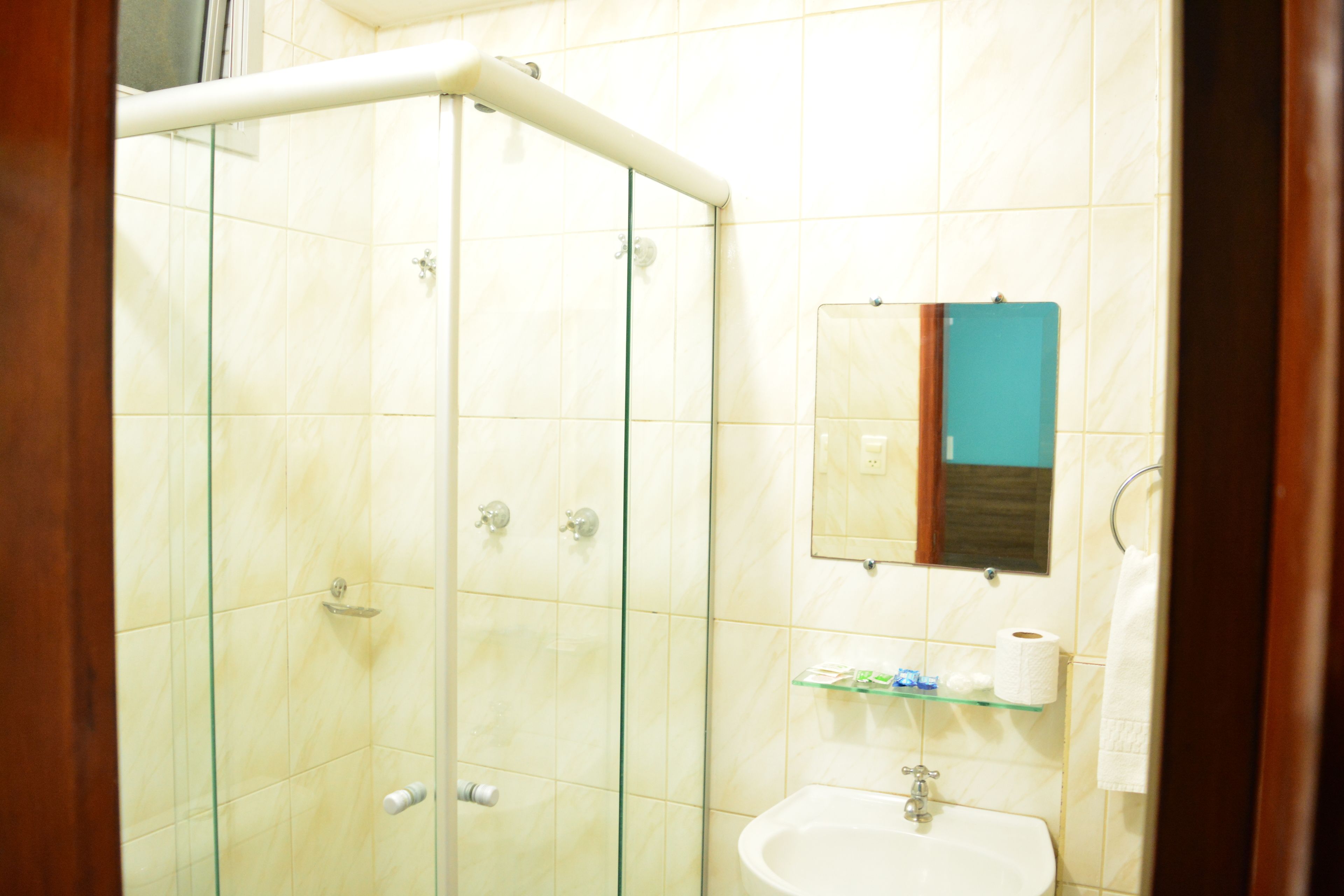 Un baño con ducha de vidrio, lavamanos y espejo.