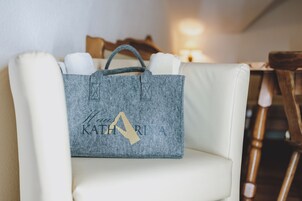 Una bolsa de tela gris con el nombre 'Katharina' en relieve, sobre una silla blanca.