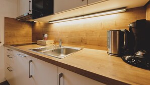 Een moderne keuken met een roestvrijstalen spoelbak, een houten aanrechtblad en inbouwapparatuur.