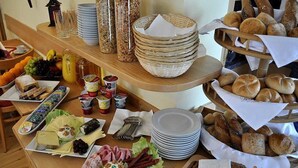 Een ontbijtbuffet met diverse producten, waaronder brood, gebak, fruit en drankjes.