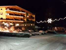 Un edificio con varios balcones, suelo cubierto de nieve y luces colgantes.