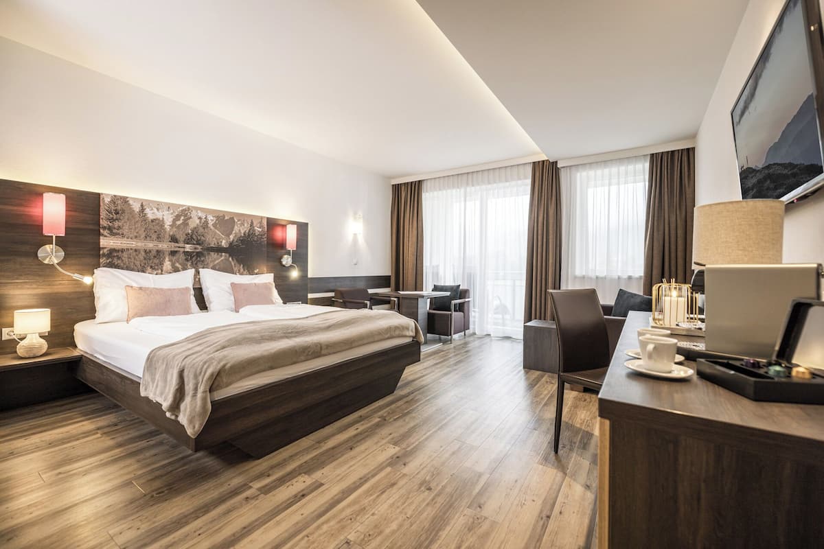 Habitación de hotel con una cama grande, un escritorio con computadora, una silla y un televisor.