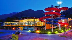 A modern building with a glass facade and a water slide structure in front.