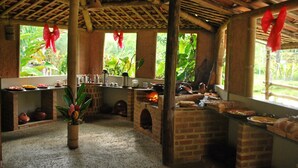 Uma cozinha rústica com fornos de tijolo, uma ilha central e um vaso de planta.