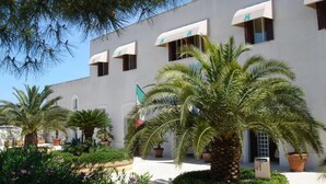A hotel with a white facade, multiple windows with awnings, and a flag. - Hotel Vecchio Mulino (Monopoli)