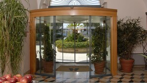 A hotel entrance with a glass door, potted plants, and a tiled floor. - Hotel Vecchio Mulino (Monopoli)
