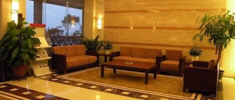 A lobby with a seating area, a reception desk, and a large window with a view.