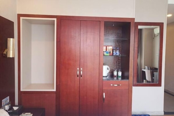 Une chambre d’hôtel avec une armoire en bois, un miroir et une petite table sur laquelle se trouvent un téléphone et quelques objets.