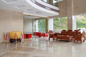 A spacious lobby with a high ceiling, a seating area with wooden furniture, and a large window offering a view of greenery outside. - Zhongmei Hotel (Jinggangshan)