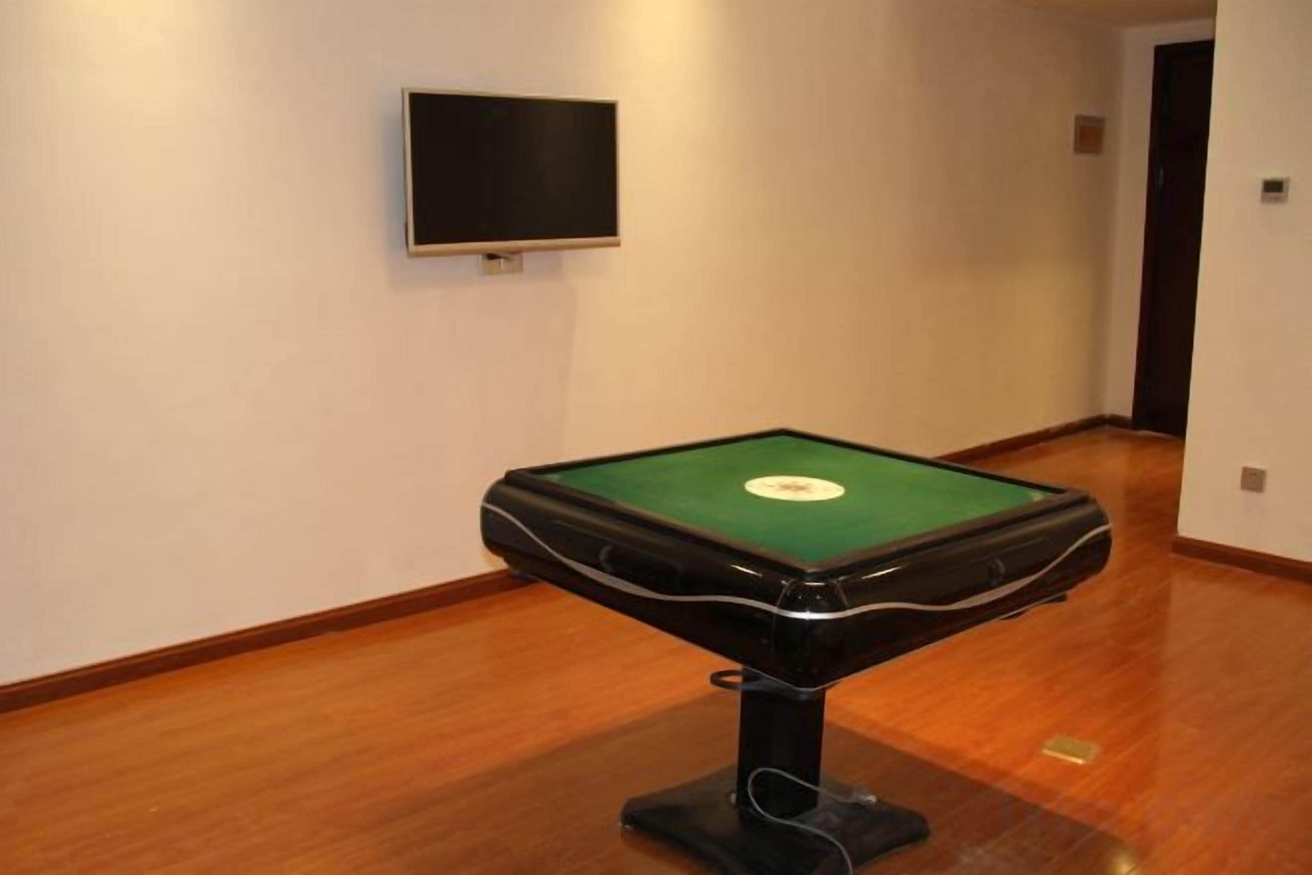 A pool table in a room with a wooden floor and a wall-mounted television.