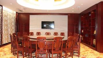 A conference room with a round table, chairs, a television, and a patterned carpet.