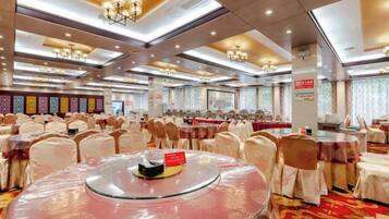 Un salón de banquetes con mesas redondas cubiertas con manteles blancos, dispuestas en filas.